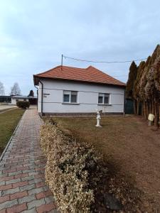 Casa blanca con techo rojo y entrada de ladrillo en Kerka Szállás, en Kerkabarabás
