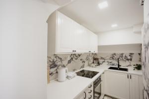 uma cozinha branca com armários brancos e um lavatório em AMORE LUXURY APARTMENT em Zagreb