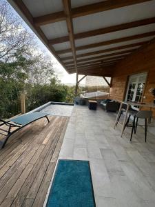 a patio with a pool and a wooden deck at Le Poppy Palm in Sainte-Luce