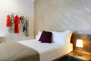1 cama con sábanas blancas y almohadas rojas en una habitación en VILLA GENTILE RESORT E SPA, en Cassano delle Murge