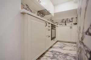 Una cocina con gabinetes blancos y piso de baldosas. en AMORE LUXURY APARTMENT, en Zagreb