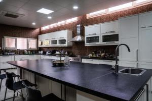 a kitchen with a black counter top and white cabinets at مزرعة واستراحة ألفي الترفيهية بالهير in Al Qaia