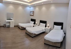 three beds in a room with white walls and wooden floors at منتجع الكناري للفلل الفندقية الفاخرة Canary resort in Taif