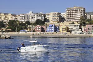 a man in a boat in the water with a city at HAPPYVILA Rustico Apartments in Villajoyosa