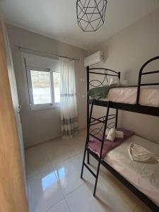 a bedroom with two bunk beds and a window at Rita's Appartements and Studios in Karpathos