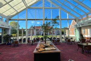 un ampio giardino d'inverno con tavolo e cibo di Milling Hotel Park a Middelfart
