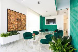卡薩諾德萊穆傑的住宿－VILLA GENTILE RESORT E SPA，一间设有绿色椅子和墙上一幅大画的等候室