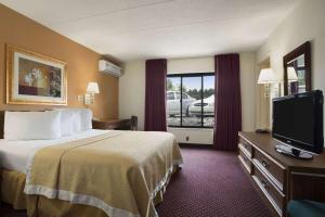ein Hotelzimmer mit einem Bett und einem Flachbild-TV in der Unterkunft Ramadaby Wyndham Pittsburgh-New Stanton in New Stanton