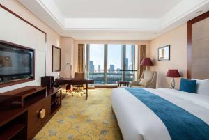 um quarto de hotel com uma cama e uma televisão de ecrã plano em Howard Johnson Tropical Garden Plaza Kunming em Kunming