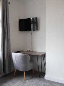 a desk with a chair and a television on a wall at Alban Suites in Saint Albans