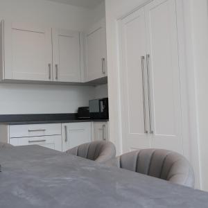 a kitchen with white cabinets and a table and chairs at Alban Suites in Saint Albans