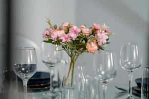 un jarrón lleno de flores rosas en una mesa con gafas en Dwupoziomowy Apartament Żmigrodzka z Tarasem w Poznaniu by Renters en Poznan