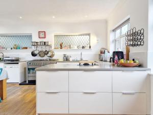 a kitchen with white cabinets and a counter top at Coastal - Wittering in West Wittering