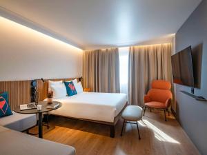 ein Hotelzimmer mit einem großen Bett und einem Schreibtisch in der Unterkunft Novotel Nice Arenas Aeroport in Nizza