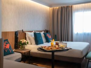 Una habitación de hotel con una cama con una bandeja de comida. en Novotel Nice Arenas Aeroport en Niza