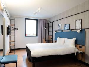 a bedroom with a large bed with a blue headboard at ibis Paris CDG Airport in Roissy-en-France