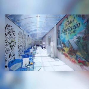 un pasillo con mesas azules y una pintura en la pared en HOTEL BLUMARIN en Lido di Jesolo