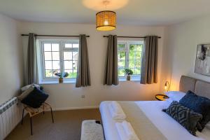 Un dormitorio con una cama y dos ventanas. en Coastal Haven Ilfracombe Charming 2-bedroom Cottage In A Great Location, en Ilfracombe