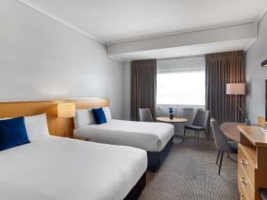 a hotel room with two beds and a desk at Novotel Perth Langley in Perth