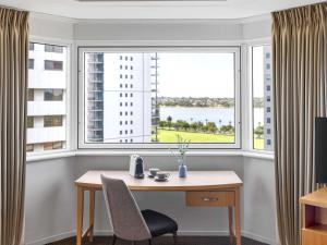 une table et des chaises devant une grande fenêtre dans l'établissement Novotel Perth Langley, à Perth