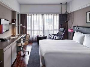 ホーチミン・シティにあるソフィテル サイゴン プラザのベッドとデスクが備わるホテルルームです。