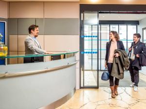 a man and a woman standing in a lobby at Aparthotel Adagio La Défense Kléber in Courbevoie