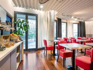 a restaurant with red chairs and tables and windows at Aparthotel Adagio La Défense Kléber in Courbevoie