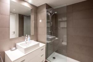 une salle de bain avec un lavabo, une douche et un miroir dans l'établissement Espais Blaus Apartments, à Barcelone