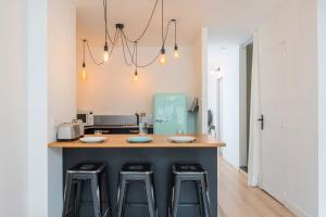 a kitchen with a counter with three bar stools at Appartement lumineux avec rooftop et garage privé. in Lille