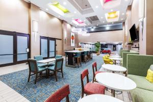 a waiting room with tables and chairs and a tv at Hampton Inn & Suites Tulsa-Woodland Hills in Tulsa