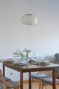a wooden table with plates and glasses on it at Spacious & Bright Apartment with Parking Poznań by Renters in Poznań