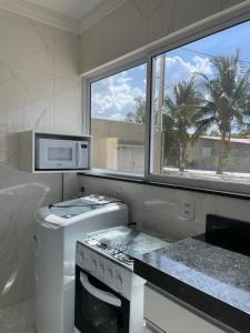 a white kitchen with a stove and a microwave at AP Locação de Diárias Lajes/RN in Lajes