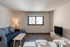 un salon avec un canapé bleu et une télévision dans l'établissement Espais Blaus Apartments, à Barcelone