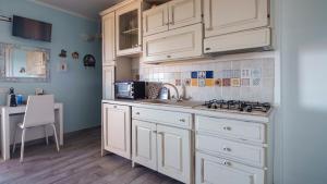 a kitchen with white cabinets and a sink and a table at Essenza Di Sardegna in Santa Marinella