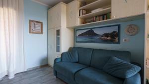 a living room with a blue couch and a book shelf at Welcomely - Essenza Di Sardegna in Marinella