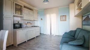 a living room with a blue couch and a kitchen at Essenza Di Sardegna in Santa Marinella