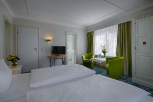 ヘリングスドルフにあるHotel Residenzのベッド、テーブル、椅子が備わるホテルルームです。