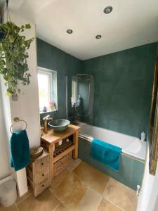 a green bathroom with a sink and a tub at Peak District Home from Home! in Grindleford Bridge