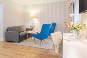 ein Wohnzimmer mit blauen Stühlen und einem Sofa in der Unterkunft NH Hamburg Mitte in Hamburg