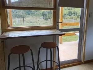 a kitchen with two stools in front of a window at LA CABAÑA DEL CAMPO in Ushuaia