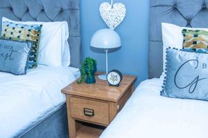 a bedroom with two beds and a table with a clock at TD M-Gold Dudley Luxurious 3 Bedroom House - Sleeps 8 - Perfect for Leisure, Families, Business Long and Short Stay - Free Parking 