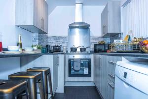 a kitchen with a stove and some stools in it at TD M-Gold Dudley Luxurious 3 Bedroom House - Sleeps 8 - Perfect for Leisure, Families, Business Long and Short Stay - Free Parking 