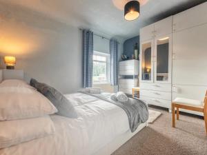 1 dormitorio con 1 cama blanca y 1 silla en Pass the Keys Cosy Miners Cottage, en Telford