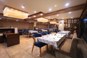 a restaurant with white tables and blue chairs at SN Blu Hotel in Ahmedabad