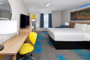 a hotel room with a bed and a desk and a television at Days Inn & Suites by Wyndham Sellersburg in Sellersburg