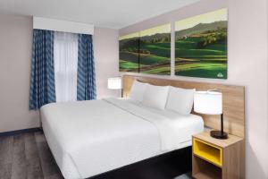 a bedroom with a white bed and paintings on the wall at Days Inn & Suites by Wyndham Sellersburg in Sellersburg