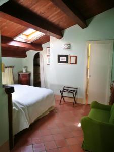 a bedroom with a white bed and a green chair at La Zizzania e il Mandarino in Roccagloriosa