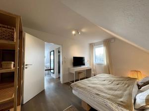 a bedroom with a bed and a desk with a television at Steuerbord Nock mit Hund in Wangerland