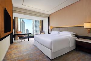 a bedroom with a large white bed and a desk at Sheraton Grand Jakarta Gandaria City Hotel in Jakarta