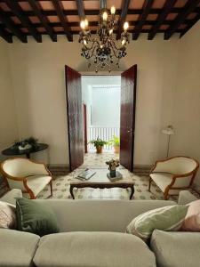 a living room with a couch and chairs and a chandelier at GINVA - Casa palacio La Templanza in El Puerto de Santa María